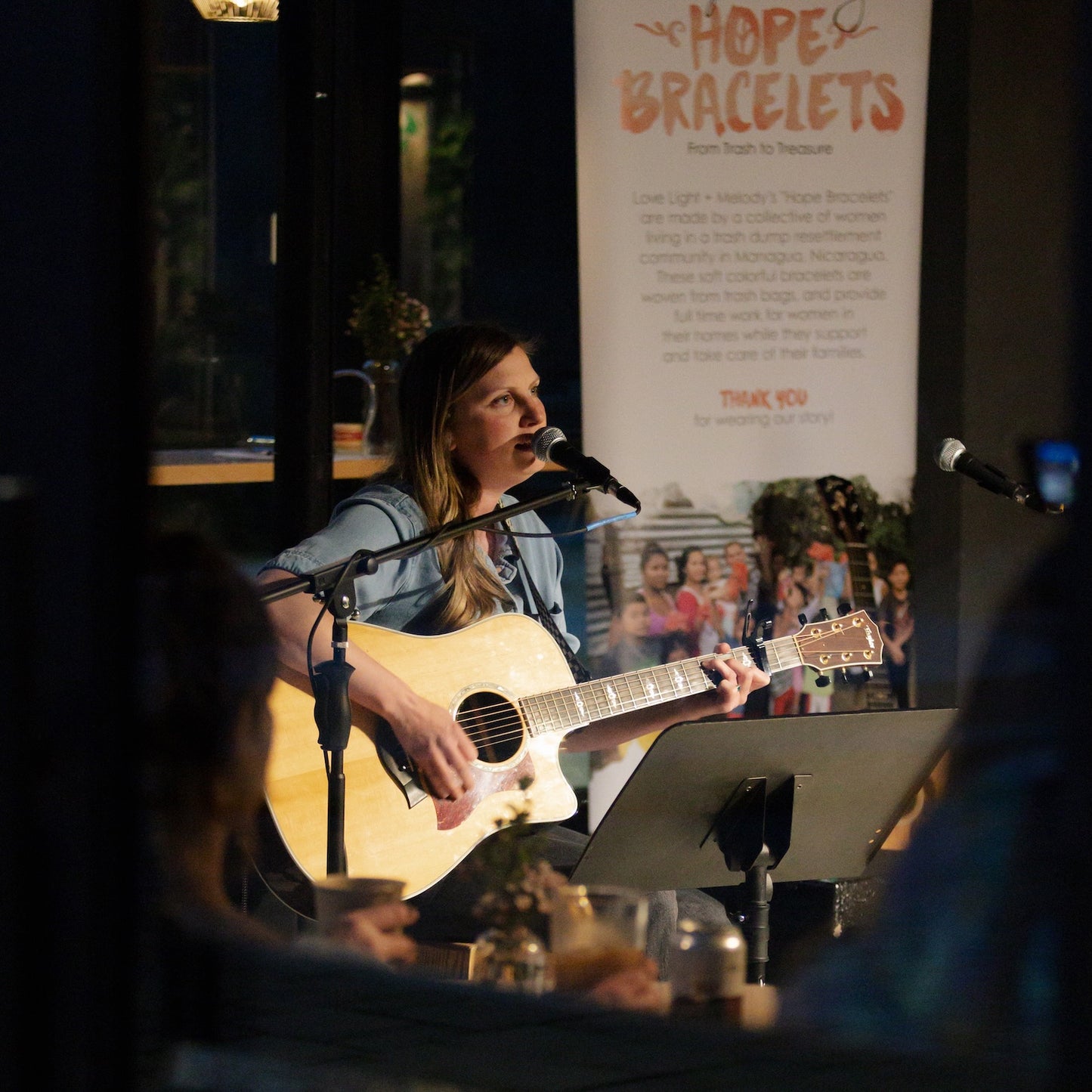 Woman playing guitar and singing into a microphone 